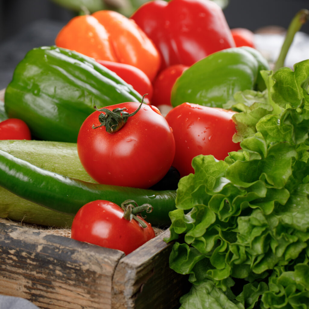 tomatoes, cucumbers, greenery in a wooden tray.